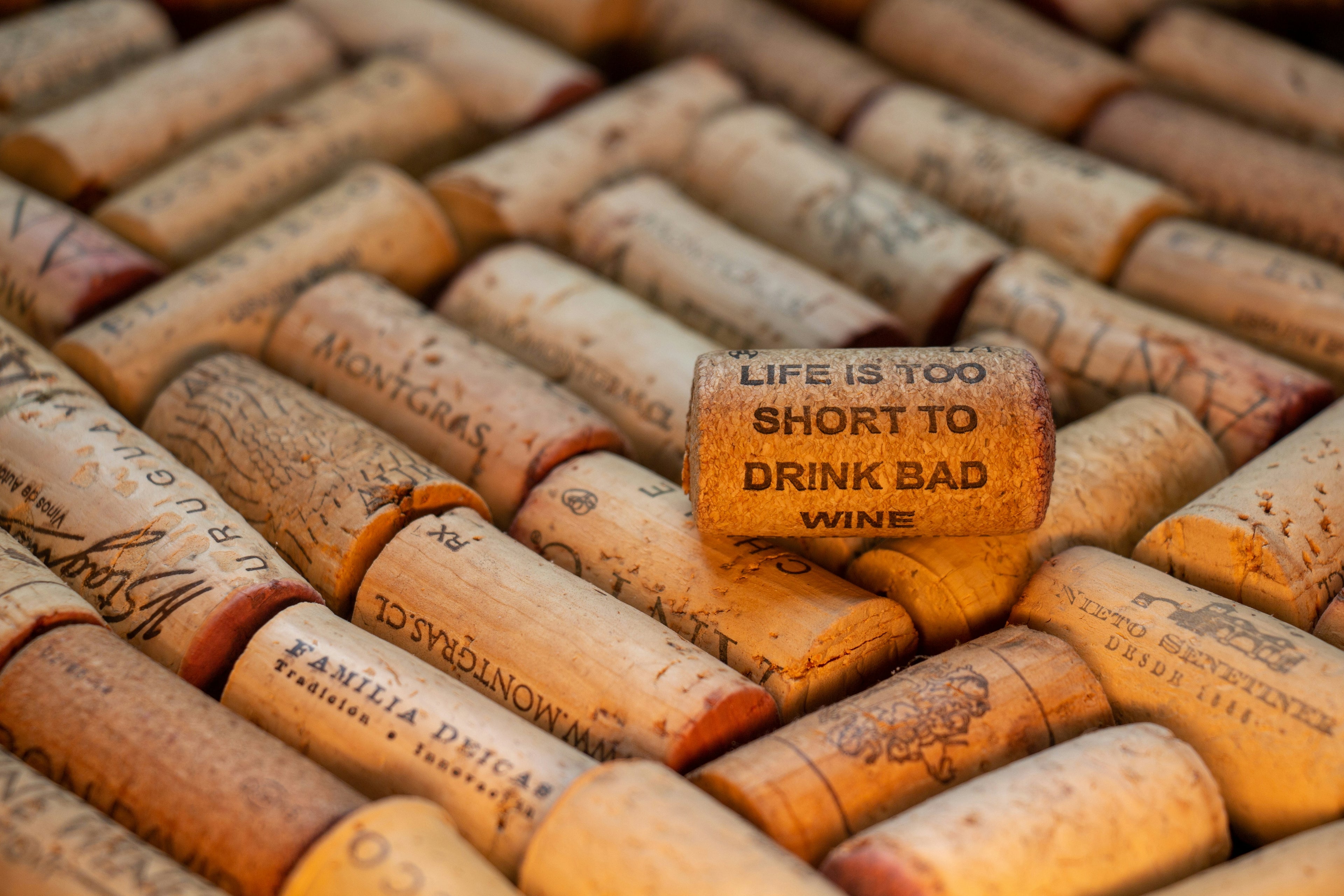 Een verzameling wijnkurken met op de voorgrond een kurk met de gegraveerde tekst ‘Life is too short to drink bad wine’